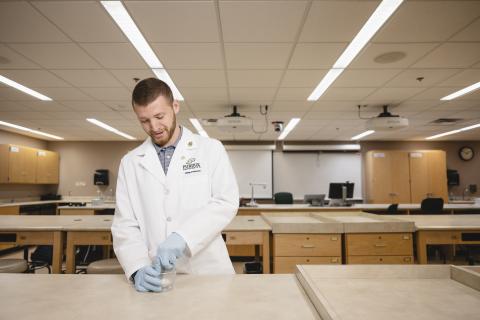 Purdue Pharmacy student works in a lab using a mortar and pestle.