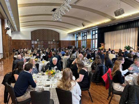 A wide-angled shot of a ballroom full of scholarship donors sitting at tables.