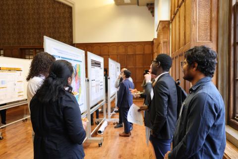 College students stand and review large research posters.