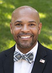 Headshot of a bald black man wearing a Purdue bowtie with a black suit.